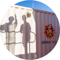 The shadow of two workers against an Alinta Energy-branded container unit.