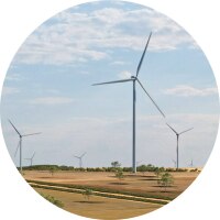 Wind turbines on a grassy plain under a partly cloudy sky with warm sunlight.